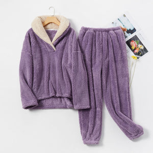 Purple plush pajama set with cream shawl collar pullover and matching pants, flat lay beside magazines