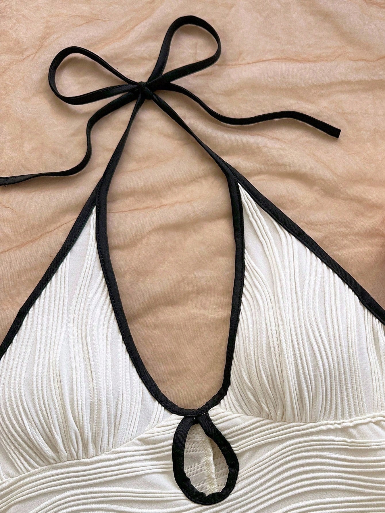 Halter neck bodycon romper in white rippled stretch fabric with a self tie bow and keyhole cutout