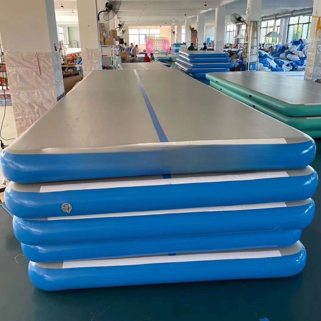 Stack of blue inflatable air track mats with a gray top and a blue center stripe in a factory