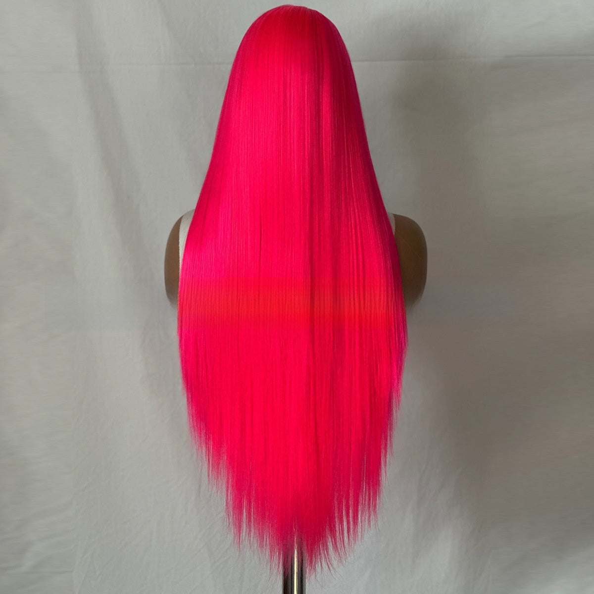 Back view of a long straight rose pink synthetic wig on a mannequin against a grey backdrop