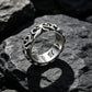 Size US 10 option photo of the silver gray scrollwork band ring on dark rock with engraved lettering inside