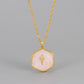 Blush pink swirled enamel cross pendant on a gold tone chain, raised gold cross centred on the hexagon medallion