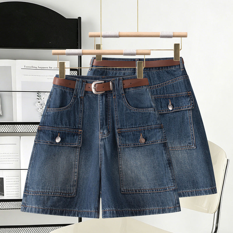 Two washed blue denim high waist cargo shorts on wooden hangers with brown belts
