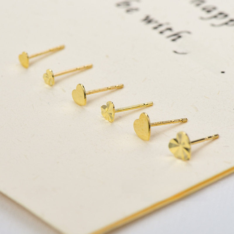 Mini heart gold stud earrings arranged top down to show the heart shape and size