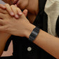 Black screenless smart bracelet worn on the wrist while the hands are clasped together