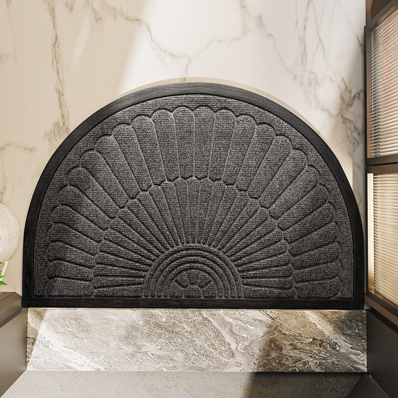 Dark gray semi circular door mat with peacock fan relief on a modern tiled floor