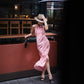 Full length pink cherry gingham dress with side slit at a bar counter