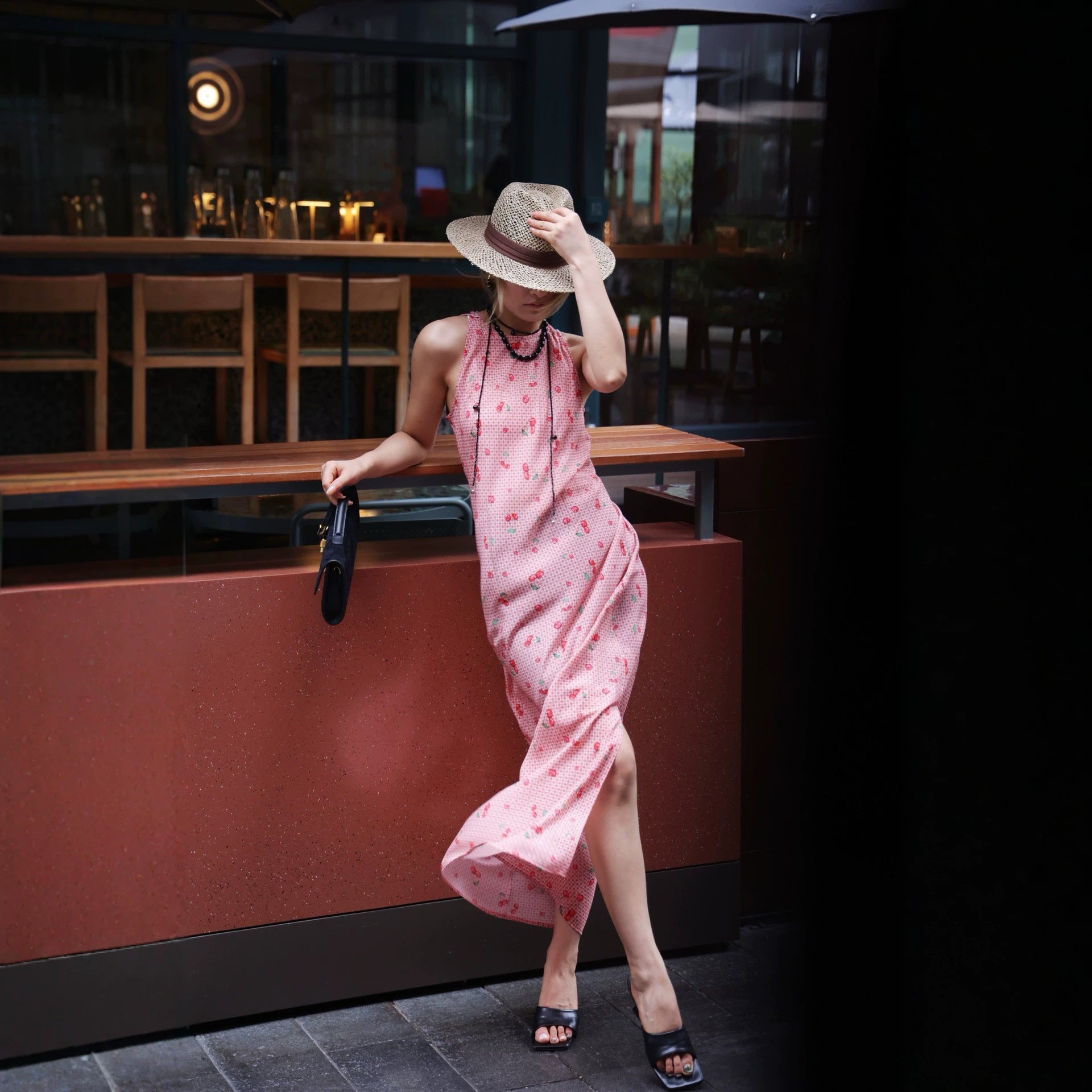 Full length pink cherry gingham dress with side slit at a bar counter