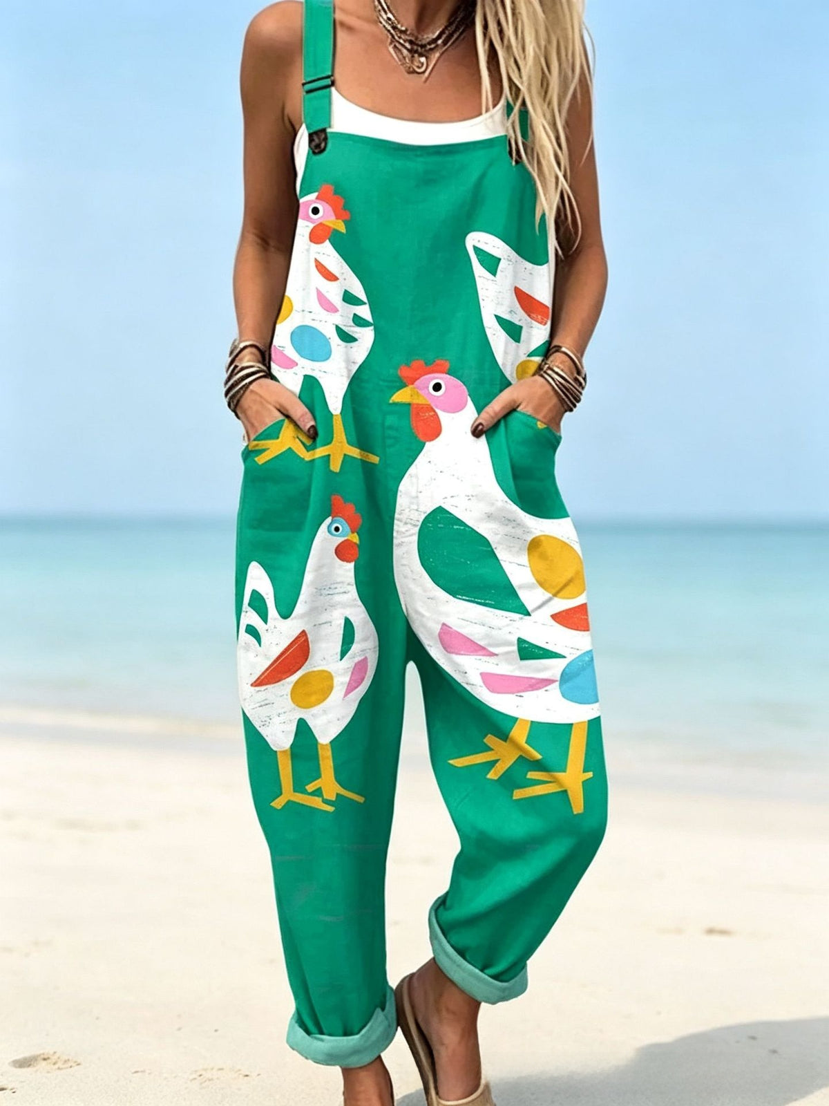 Size 4XL option: Emerald green overalls with a large white chicken print, cuffed legs and pockets on a beach