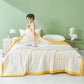 White seersucker summer quilt with a cloud yellow border on a styled bed by a green wall