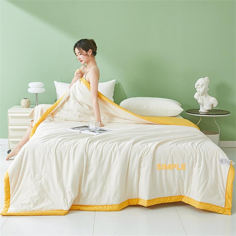 White seersucker summer quilt with a cloud yellow border on a styled bed by a green wall