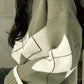 Matcha green knit sweater with cream argyle diamonds, side view showing the dropped shoulder and ribbed cuff