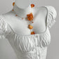 Close up of the square elasticated neckline and puff sleeve caps of the white collarless blouse