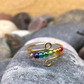 Mixed color bead spinner ring on a gold tone band, beads spin freely under a fingertip