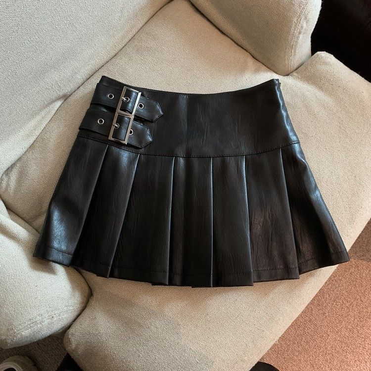 Black with Buckle Straps variant, size M: black pleated mini skirt with two buckle straps on a cream sofa