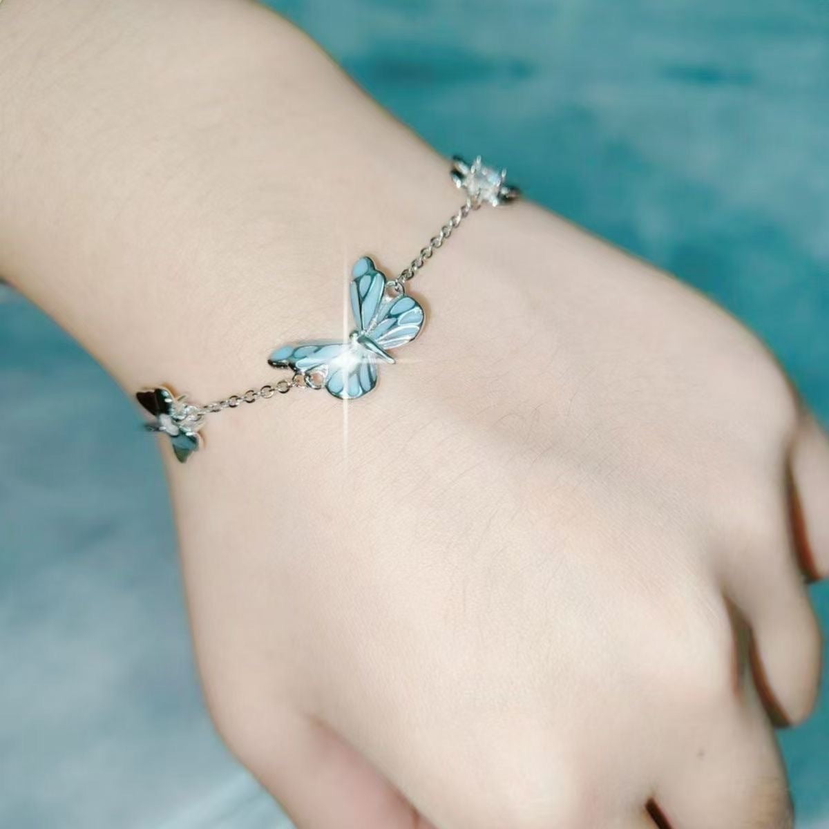 Close view of the blue enamel butterfly pendant on a silver tone chain