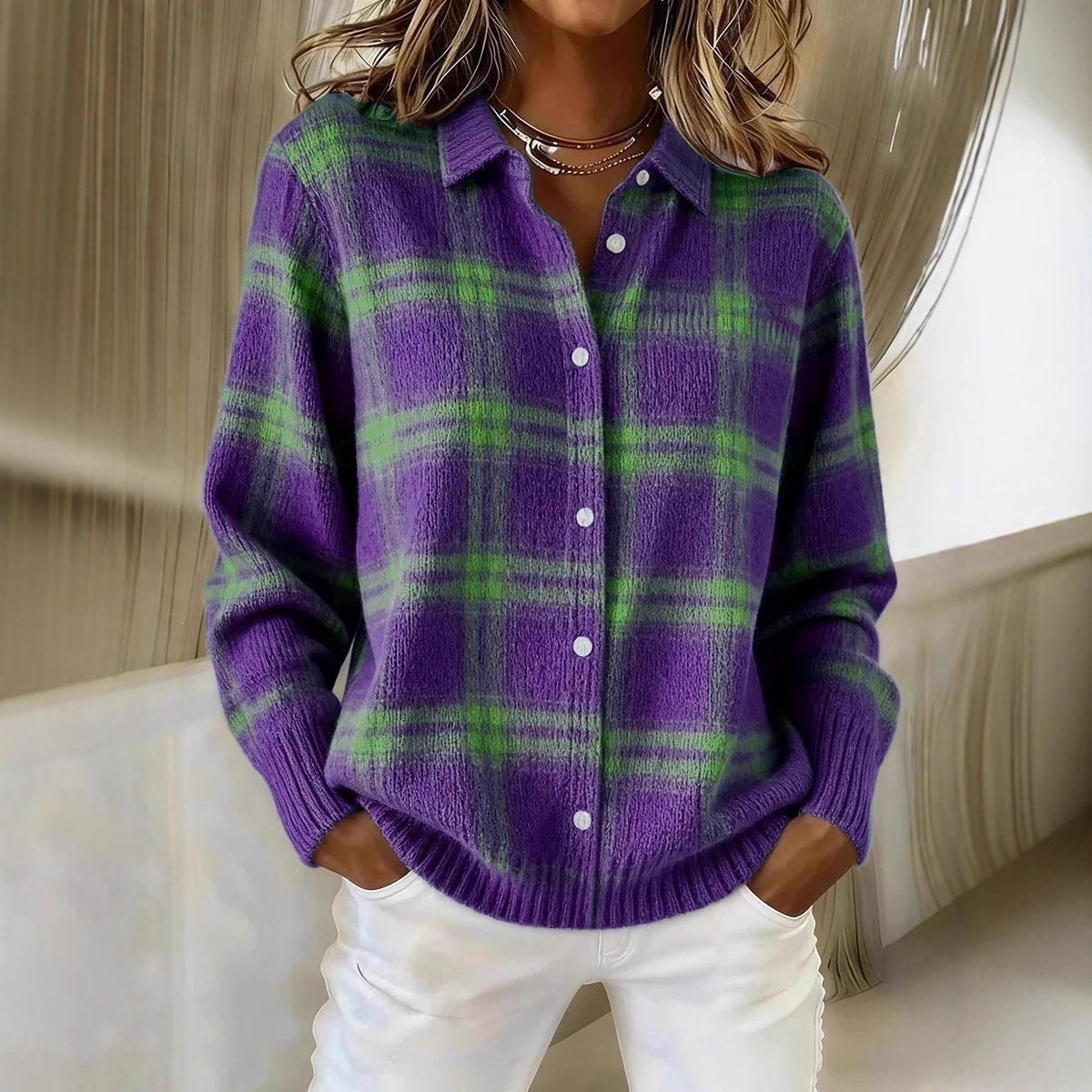 Woman in a purple plaid knit cardigan with green check, shirt collar and white buttons, hands in white trousers