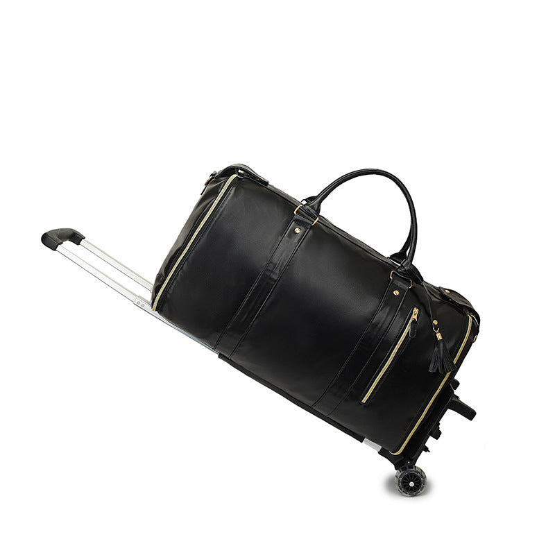 Black duffel travel bag with gold toned zips, two top handles, a telescopic handle and two wheels