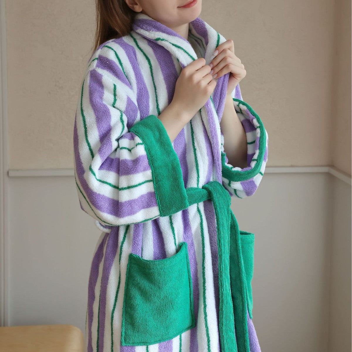 Lilac purple and green striped hooded cotton bathrobe with green trim, patch pocket and tie belt worn standing