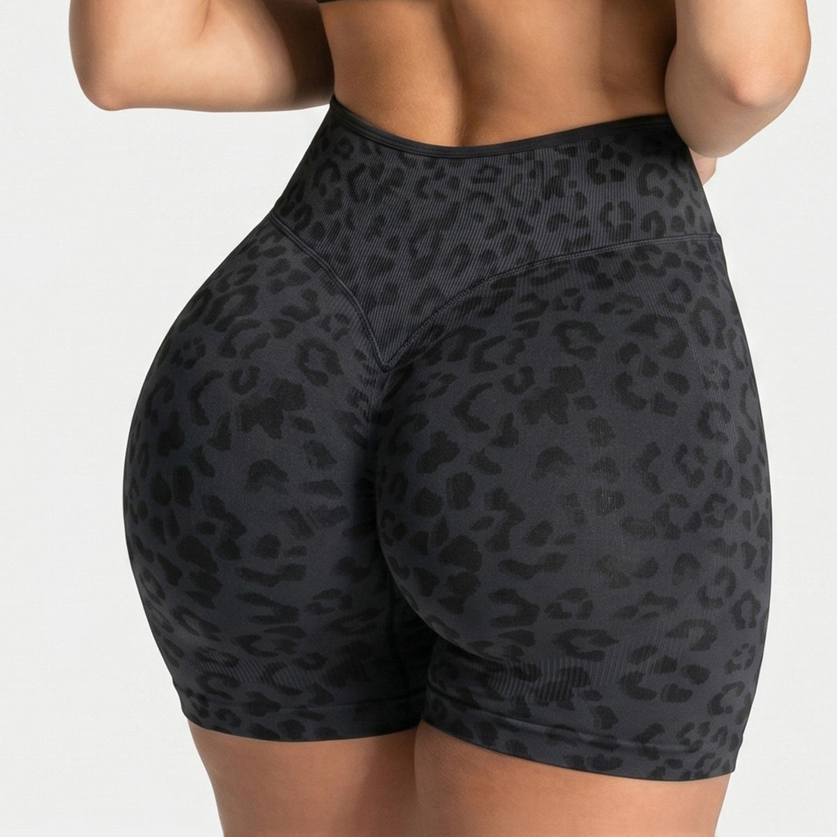 Back view of black seamless high waist yoga shorts with a tone on tone leopard print and ribbed waistband