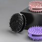 Silicone scalp brushes in purple, pink and black showing the swirling bristle heads