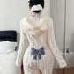 Back of a white plush hooded romper with a raised cable-style texture and a blue bow