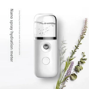 White handheld nano facial mister with clear water tank beside dried lavender sprigs