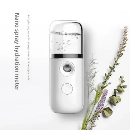 White handheld nano facial mister with clear water tank beside dried lavender sprigs