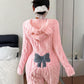 Back of a pink plush hooded romper with a raised cable-style texture and a blue bow