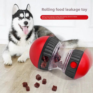 Husky beside a red rolling food dispensing tumbler ball with treats falling out