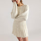 Woman in a cream cable knit sweater dress with full sleeves and her arms crossed, front view