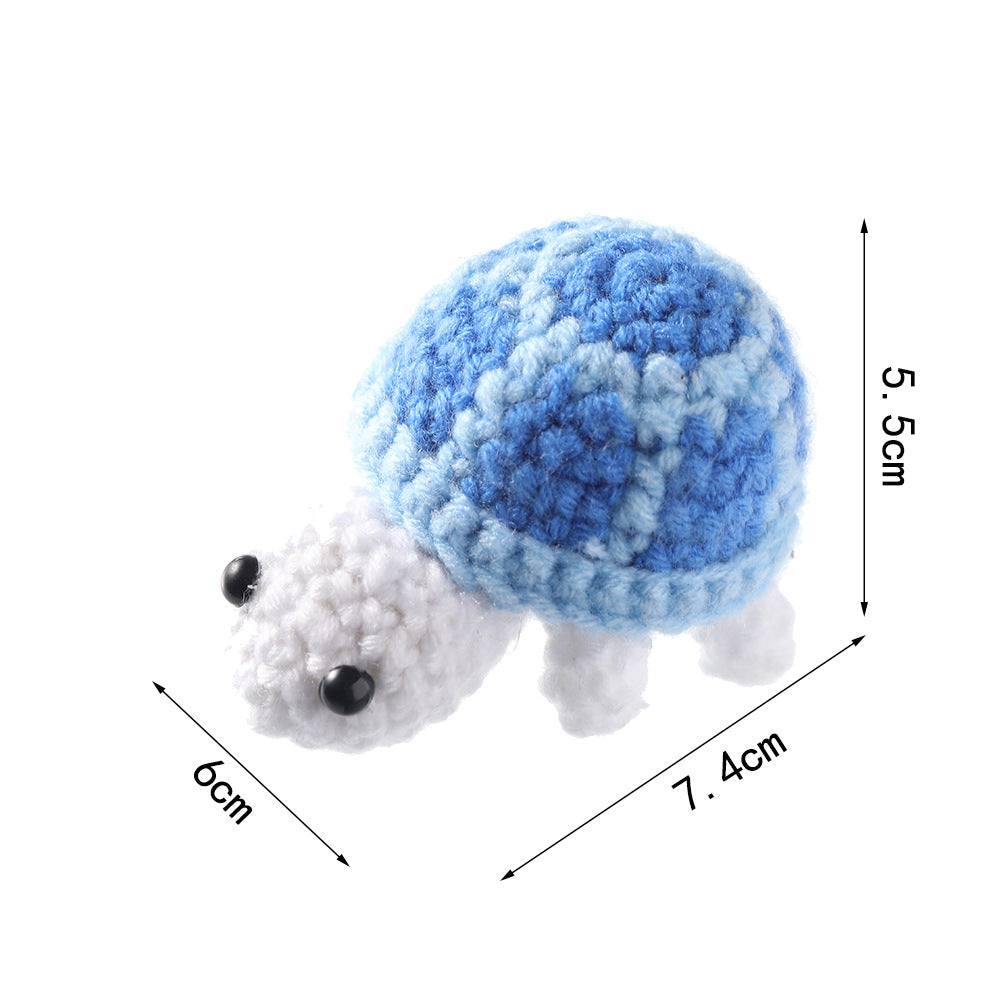 Blue crocheted turtle with a white head on white, marked 7.4 cm long, 6 cm wide and 5.5 cm high