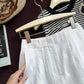 Close view of white linen shorts high waist beside a straw bag and book