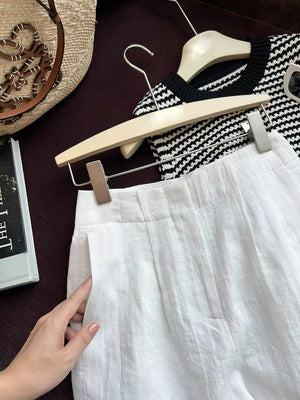 Close view of white linen shorts high waist beside a straw bag and book