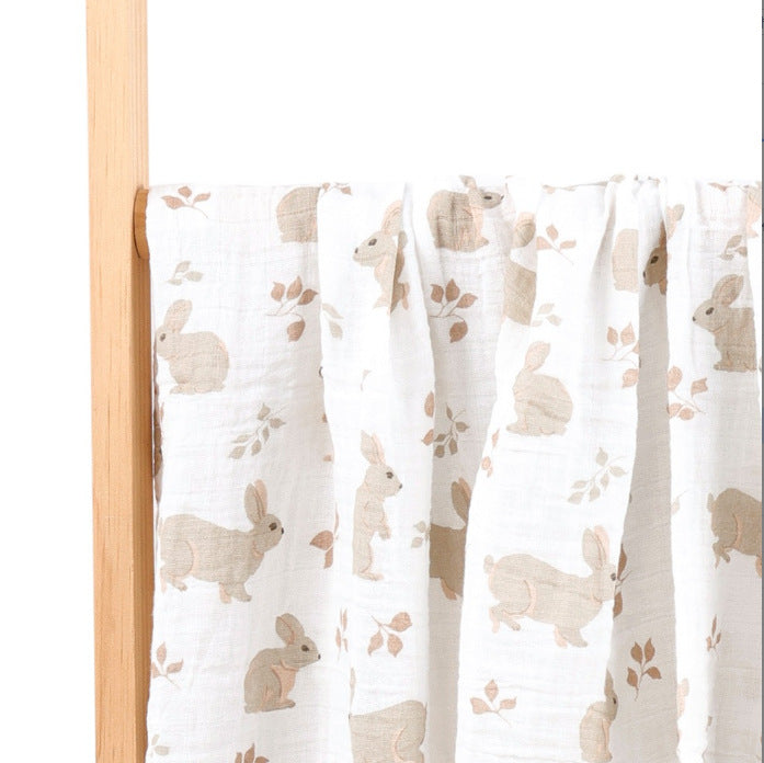 Folded cotton muslin swaddle blanket with a soft open weave and an even printed pattern