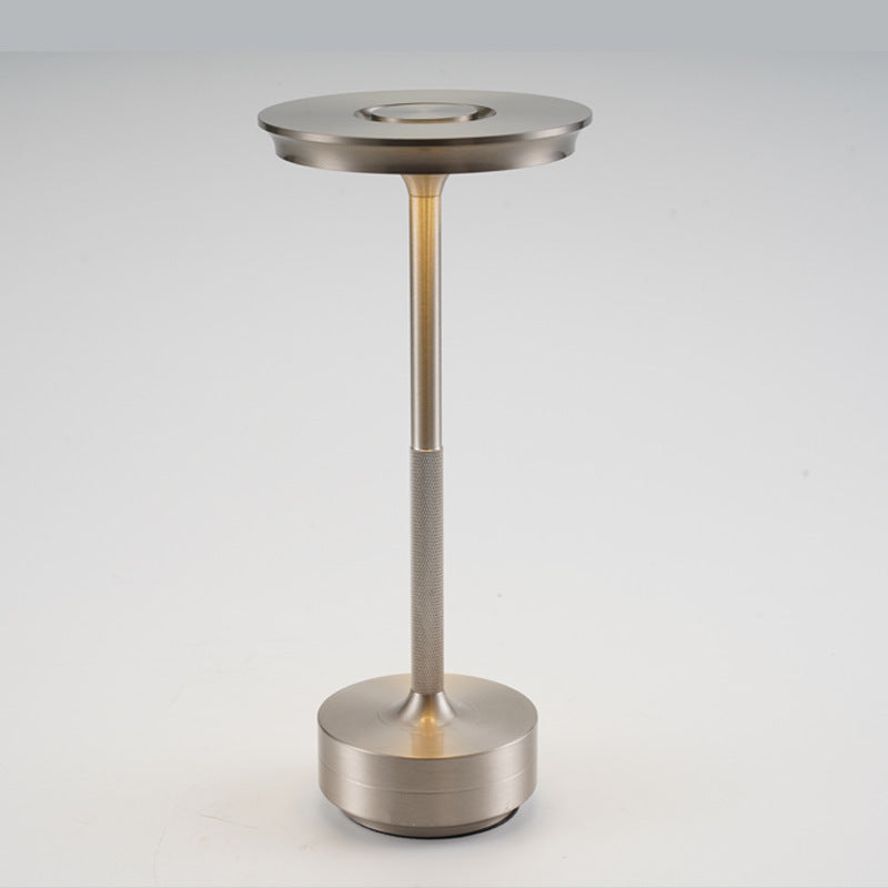 Silver table lamp with a knurled grip band on the slim stem and a round base on a light background