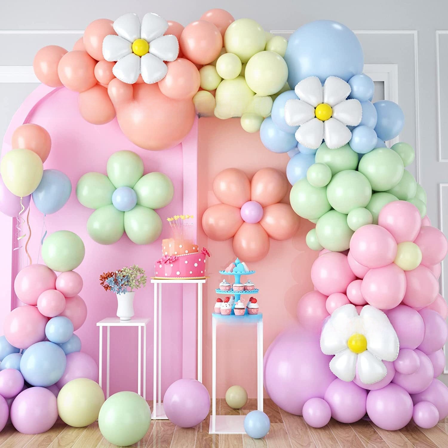 Birthday brunch table framed by a pastel balloon and daisy garland in daylight