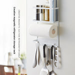 White iron magnetic storage rack on a fridge side holding spice jars and a paper towel roll