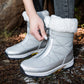 Hand pulling the front metal zipper of a silver plush cuffed snow boot outdoors