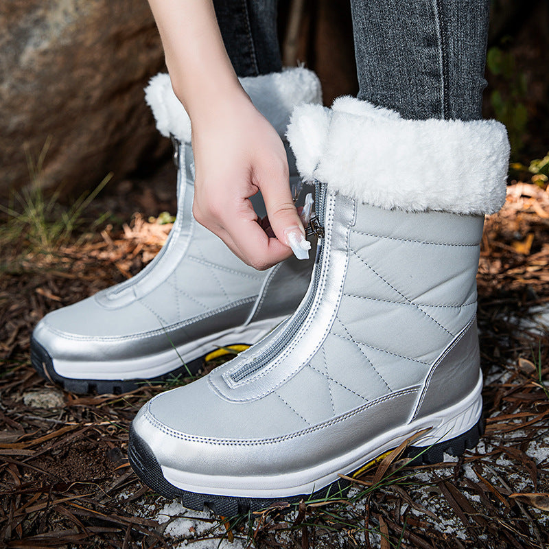 Hand pulling the front metal zipper of a silver plush cuffed snow boot outdoors