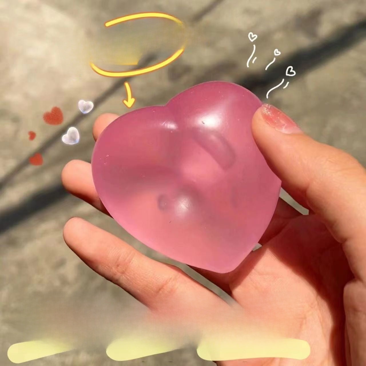 Frosted pink colour changing heart squeeze toy held in a hand, pale patches where pressed