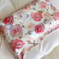 Romantic rose print silk pillowcase with large pink and mauve roses on a bed