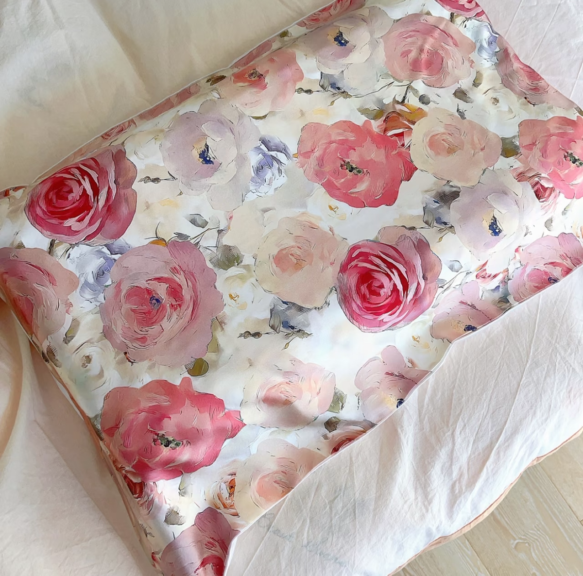 Romantic rose print silk pillowcase with large pink and mauve roses on a bed