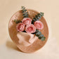 Pink glazed ceramic cowboy hat vase holding pink roses and eucalyptus