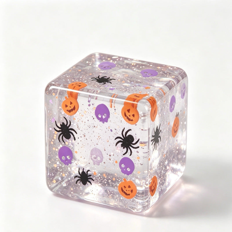 Clear glitter Halloween squishy stress cube with orange pumpkins and purple skulls