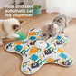 Two cats crouched at the edge of a graffiti print star cat teaser mat with the green feather wand out