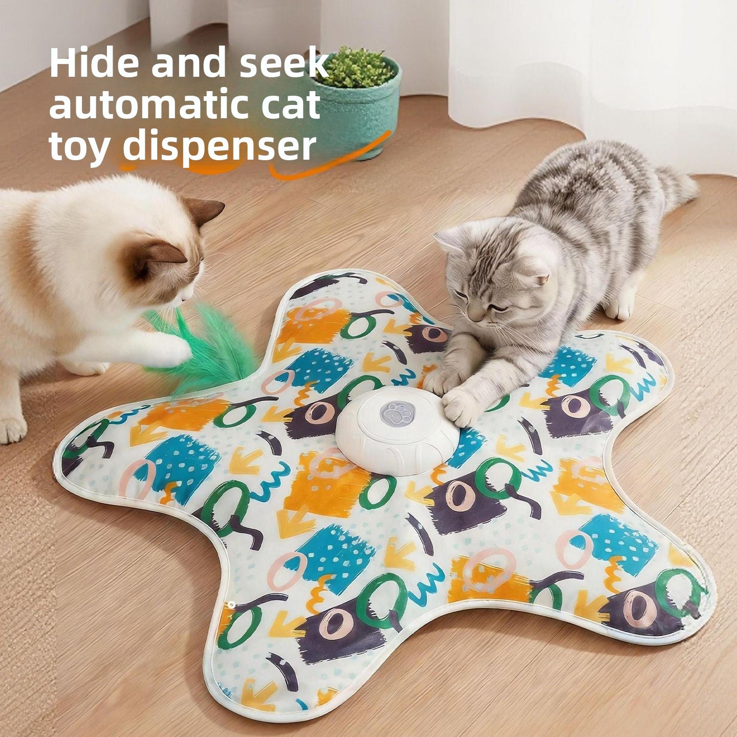 Two cats crouched at the edge of a graffiti print star cat teaser mat with the green feather wand out
