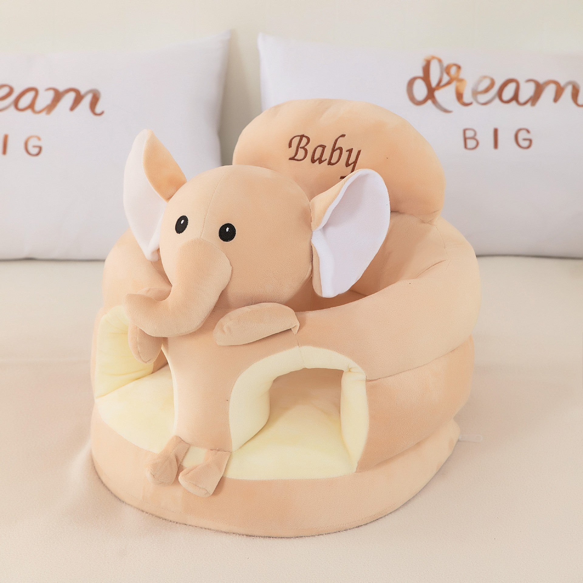 Beige plush baby floor seat with an elephant at the front and a padded seating ring