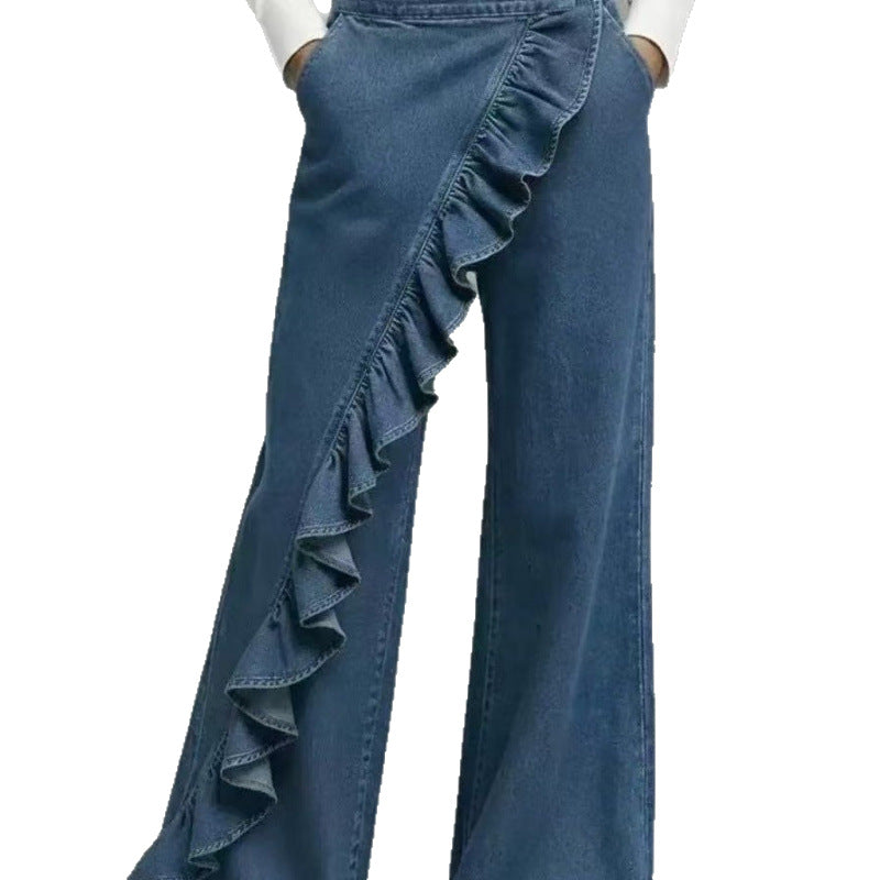 Dark blue wide leg denim trousers with a diagonal ruffle falling long over pointed shoes