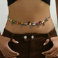 Corded waist chain with coloured beads and silver tone leaf charms, worn over brown trousers